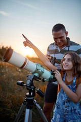 Father and daughter observing the sky with a telescope.