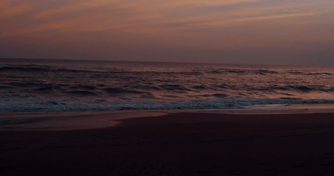 Black sand beach and sea water at beautiful sunset - video in slow motion
