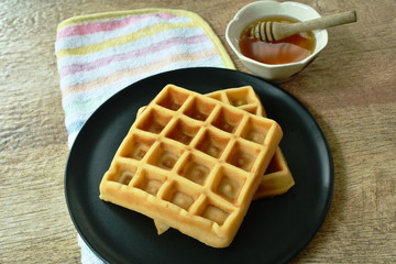 baked butter waffle on plate with honey syrup cup
