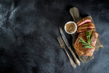 Fototapeta na wymiar Cooked ready meat, Grilled beef steak with rosemary, on cutting board