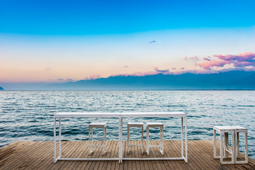 White table and chairs against the blue lake. Located in Erhai Lake, Dali, Yunnan, China.