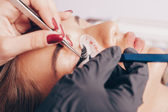 Beautiful young woman at eyelash extension procedure. Cosmetics and body care close up shot.