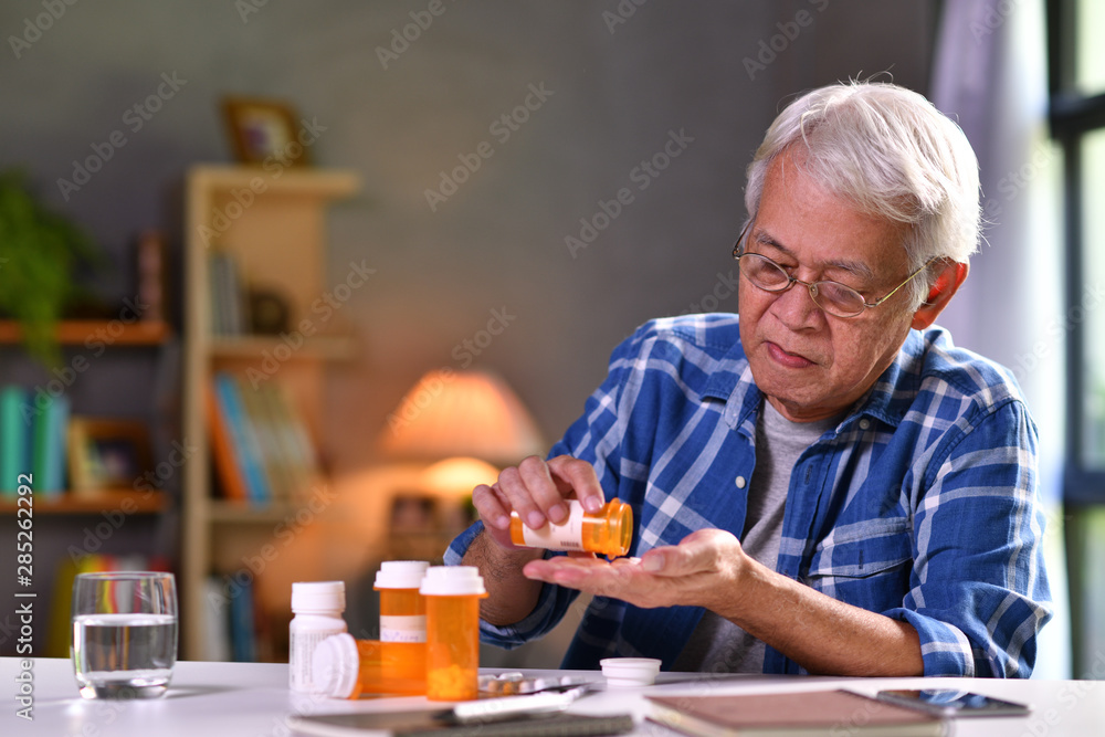 Wall mural asian senior man taking medicine at home