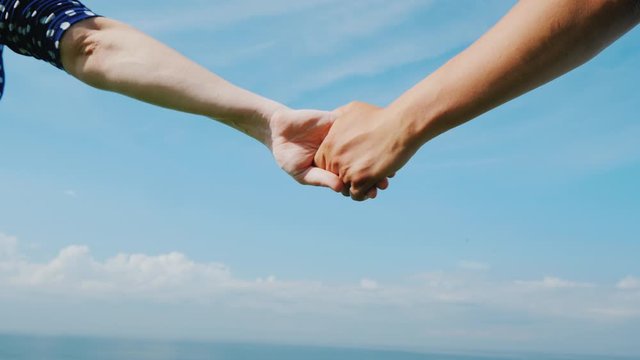 Young couple holds hands against a blue sky