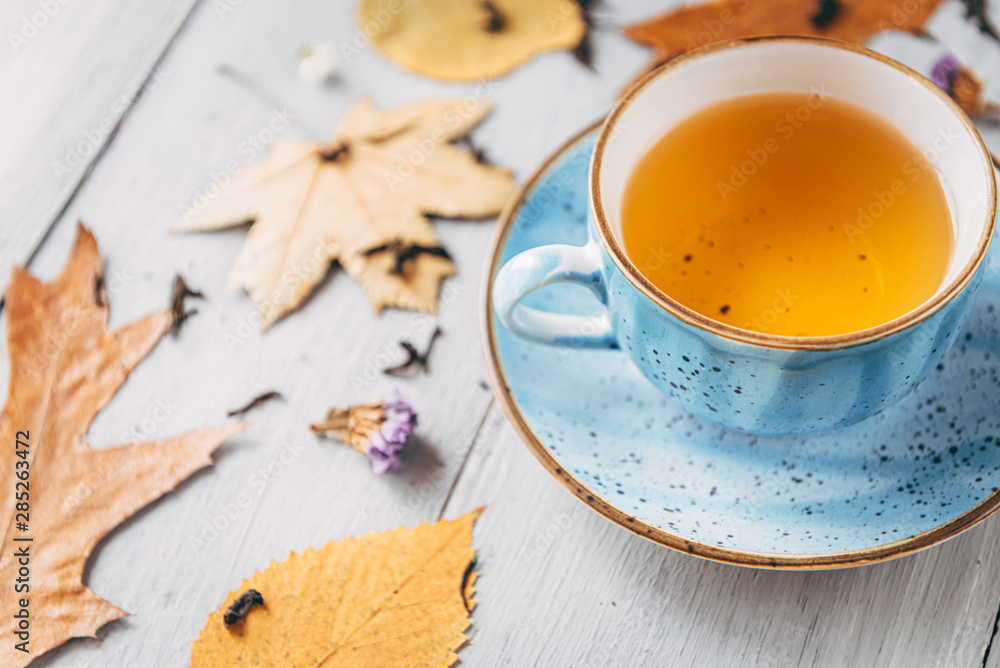 Wall mural autumn warming tea on a wooden table with autumn tree leaves lying nearby