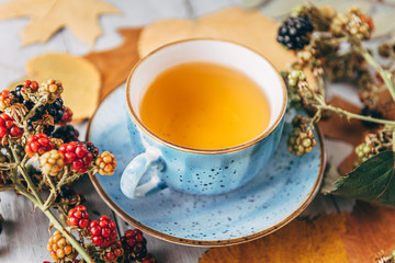 autumn warming tea on a wooden table with autumn tree leaves lying nearby