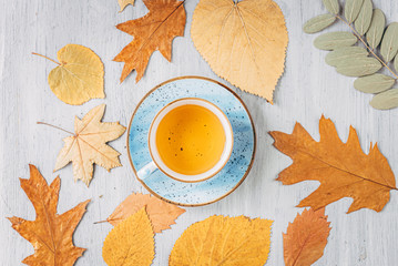 autumn warming tea on a wooden table with autumn tree leaves lying nearby