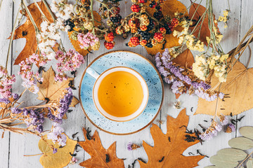 autumn warming tea on a wooden table with autumn tree leaves lying nearby
