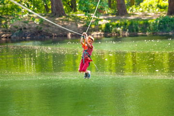 Happy boy slide on zip line with trolley over lake