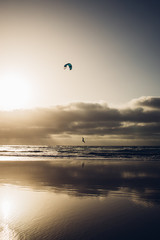 Personas practicando kitesurf al atardecer en la playa de Famara en la isla de Lanzarote