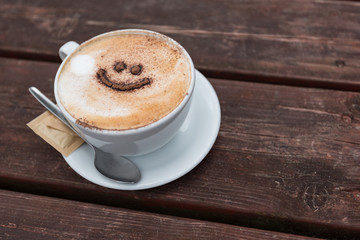 Close up of a cup of coffee with a smile face, outside in a UK beach holiday resort, Pendine Wales
