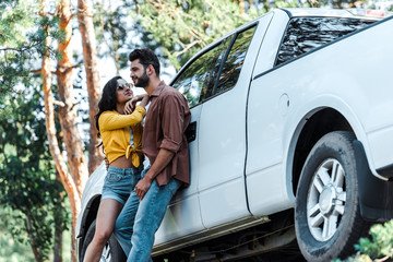 low angle view of attractive girl in sunglasses standing with bearded man near car