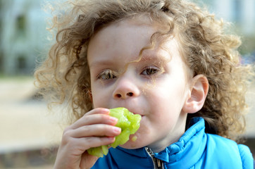 Kind mit Locken isst eine zermanschte Kiwi