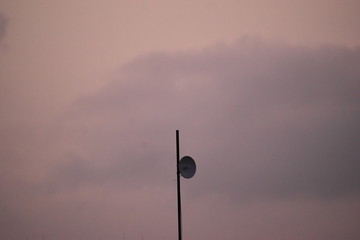 A signal transmitter attached to a pole with visible orange sky in the background 