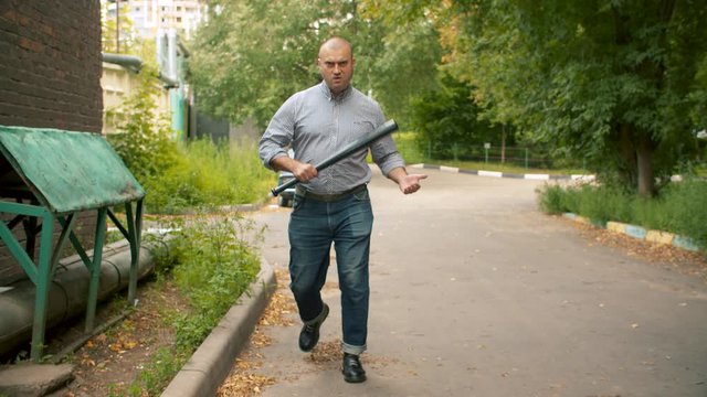 An angry bully with a baseball bat in his hands attacking someone