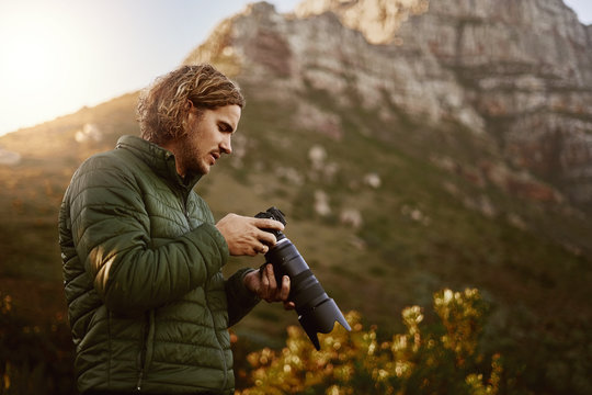 Photographer checking pictures on mirrorless camera outdoors in nature