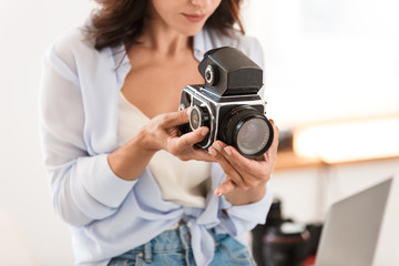 Amazing young pretty photographer woman in office holding retro old camera.