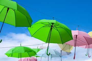 Fototapeta na wymiar colorful umbrella line decorate outdoor moving by wind on blue sky white cloud
