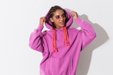 Smiling cheery happy young african stylish woman in pink sweatshirt and sunglasses posing isolated...