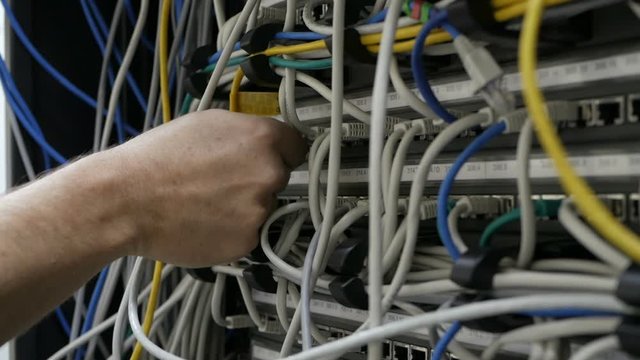 a technical IT specialist digs in the wires in search of a problem