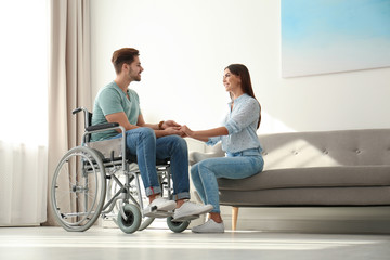 Young woman with man in wheelchair indoors