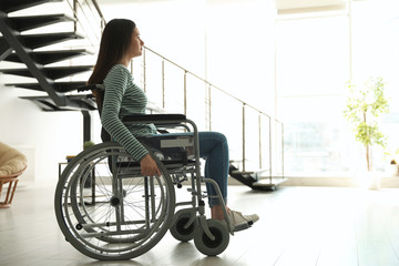 Young woman in wheelchair indoors. Space for text