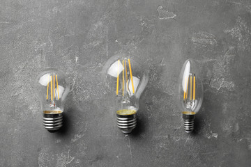 New vintage lamp bulbs on grey stone surface, flat lay