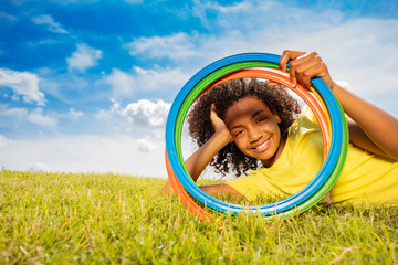 Happy young black girl looking through color hoops