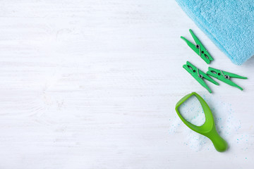 Flat lay composition with clothespins, towel and measuring scoop of laundry powder on white wooden...