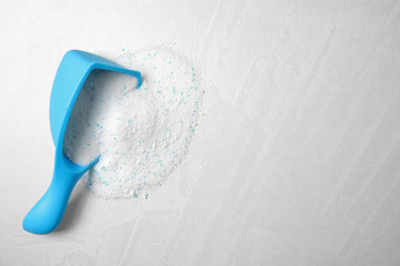 Measuring scoop with laundry detergent on light background, top view. Space for text