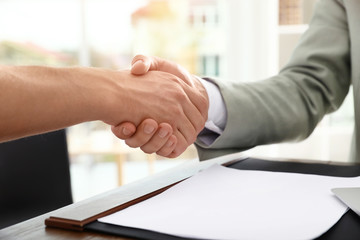 Fototapeta na wymiar Business partners shaking hands at table after meeting in office, closeup