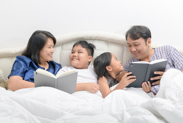 Fototapeta na wymiar Happy Family reading a story on bed in the bedroom,
