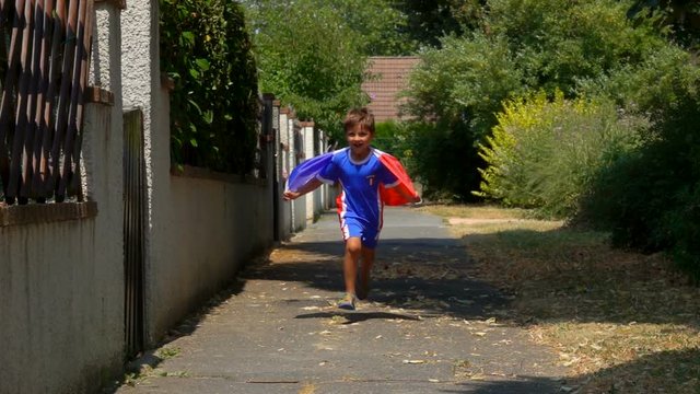 Boy fan of the French national team runs for joy with a French flag in his hands.