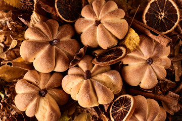 Homemade cookies in shape of pumpkin in autumn leaves. Halloween handmade cookies on a table, close up