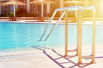 Background of water in blue swimming pool, water surface with a sun reflection