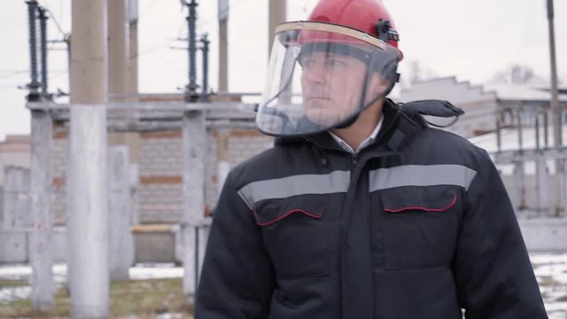 Builder man in overalls warm uniform and protective helmet with mask on construction site in northern region. Worker puts mask face works street winter. Harsh working weather conditions in building.