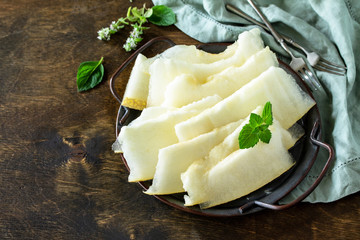 Fresh melons sliced to pieces on rustic wooden table. Free space for your text.
