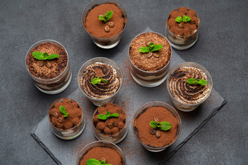Group of portions of Classic tiramisu dessert in a glass cup on stone board on concrete background
