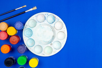 Top view close-up poster color set, Color mixing palette and two paintbrush on blue background.