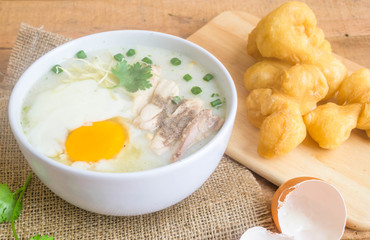Porridge, chicken Porridge (congee) and Soft-boiled egg served in white bowl with deep-fried doughstick