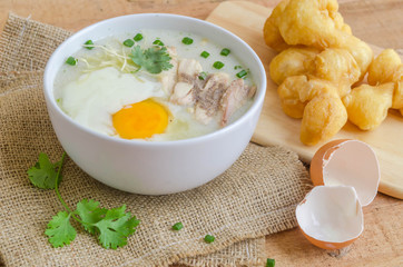 Porridge, chicken Porridge (congee) and Soft-boiled egg served in white bowl with deep-fried doughstick
