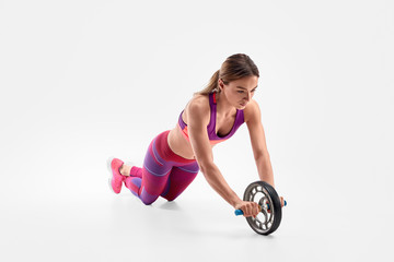 Slim woman exercising with wheel