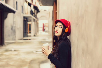 Portrait attractive beautiful woman drinking coffee and listening music. Charming beautiful woman feels lonely  and thinking something. Glamour beautiful girl stand at city. town background copy space