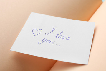 Paper sheet with words I LOVE YOU on open notebook, closeup