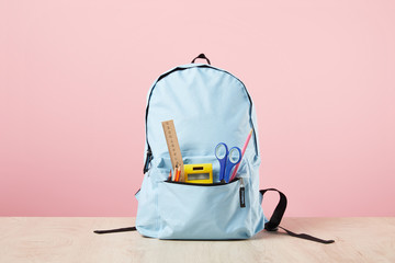 Fototapeta School blue backpack with stationery in pocket isolated on pink obraz