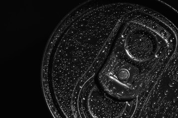 Aluminum can of beverage covered with water drops on black background, top view