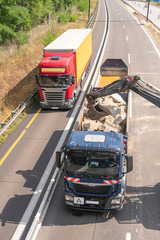 Auf einer Autobahnbaustelle wird ein LKW mit Schutt beladen und auf dem Standstreifen fährt ein...