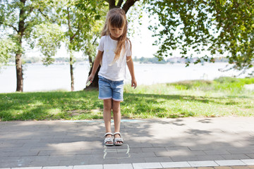 cute child  girl draws with chalk on the asphalt. Asphalt street art. Kids education. Childhood