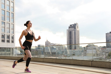 Beautiful sporty young woman running on street