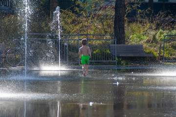 Fototapeta premium Young kid running to a water fountain